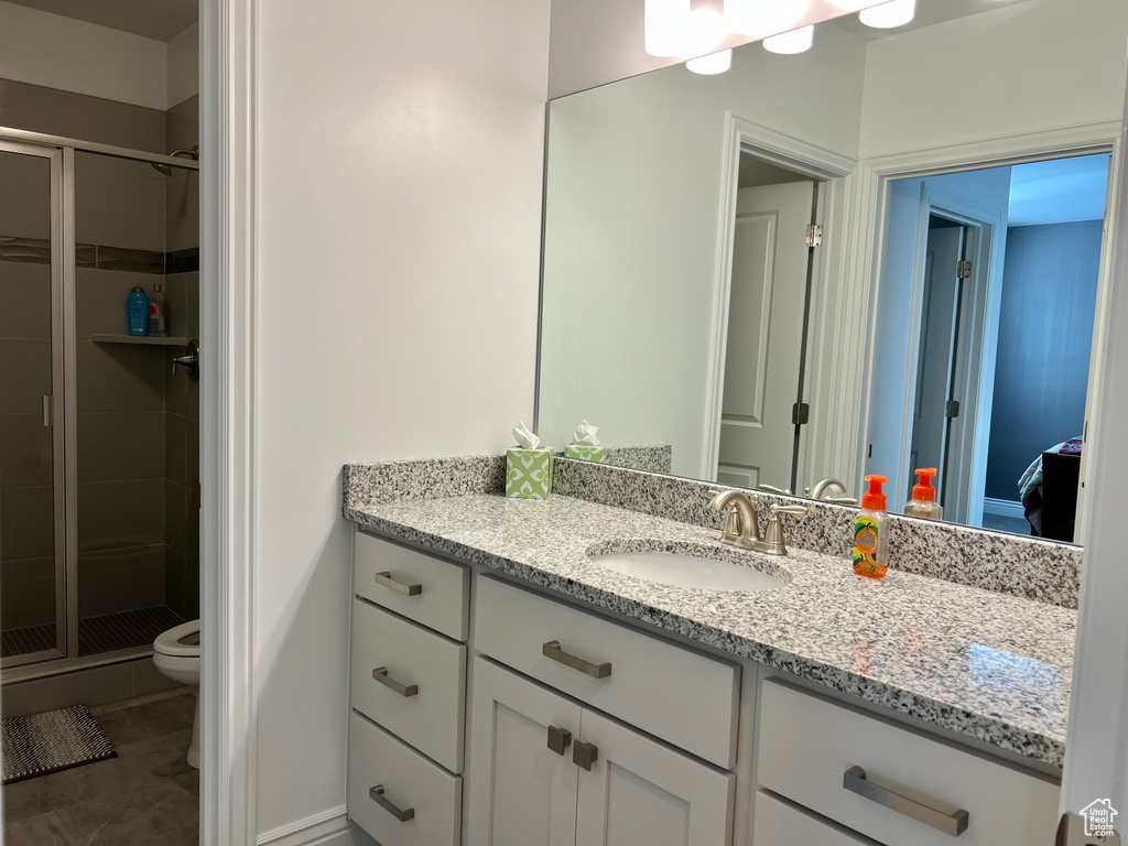 Bathroom featuring toilet, vanity, and walk in shower