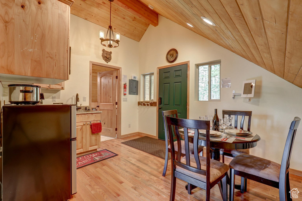 Dining space with vaulted ceiling with beams, wooden ceiling, light hardwood / wood-style floors, and a notable chandelier