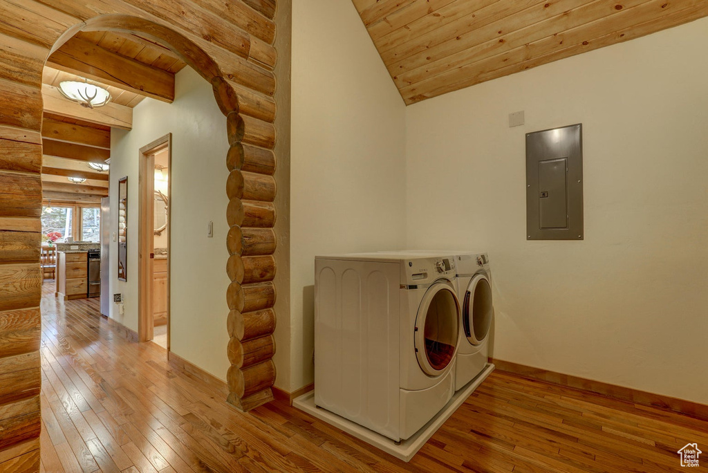 Laundry room featuring washing machine and clothes dryer, log walls, light hardwood / wood-style flooring, electric panel, and wood ceiling