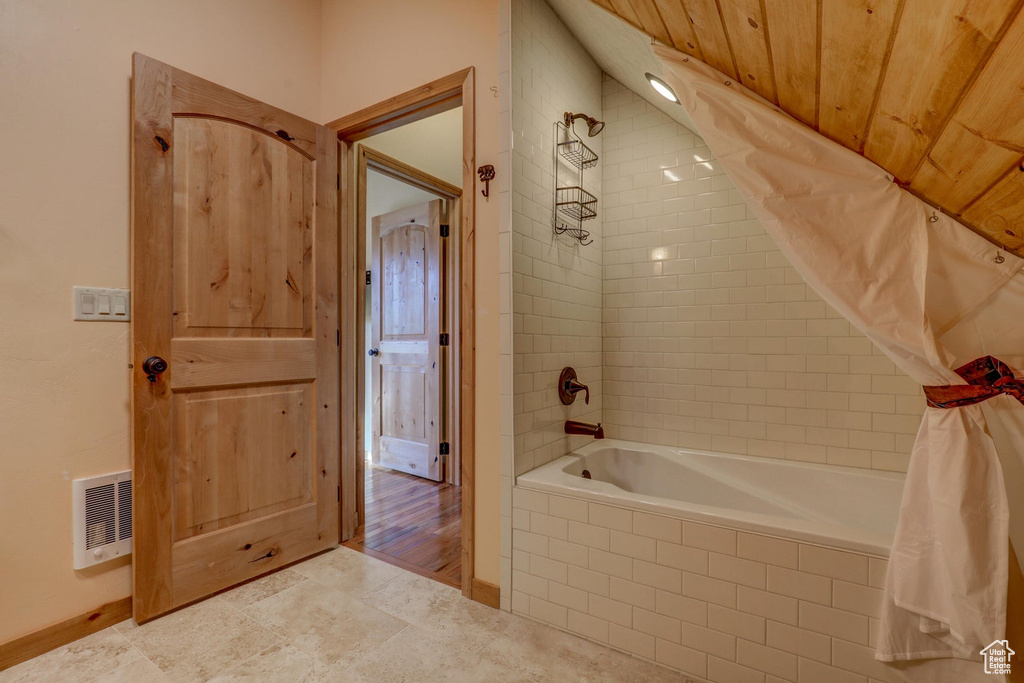 Bathroom with hardwood / wood-style floors, shower / tub combo with curtain, and wood ceiling