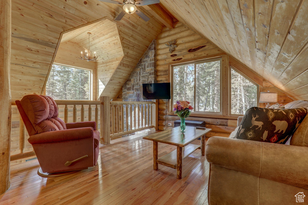 Living room featuring lofted ceiling with beams, light wood-type flooring, ceiling fan with notable chandelier, and wooden ceiling