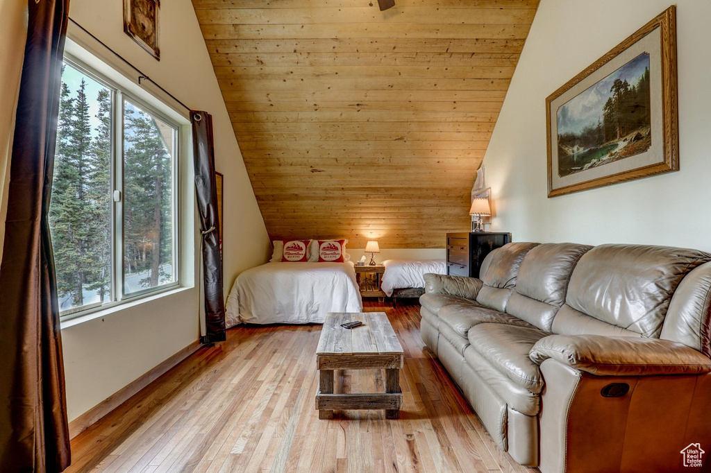 Bedroom featuring light hardwood / wood-style floors, vaulted ceiling, and multiple windows