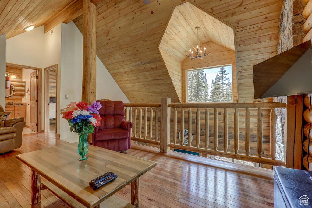 Living area with a chandelier, high vaulted ceiling, light hardwood / wood-style flooring, and wood ceiling