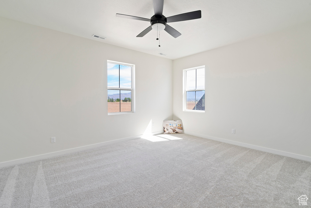 Carpeted empty room with ceiling fan and baseboards