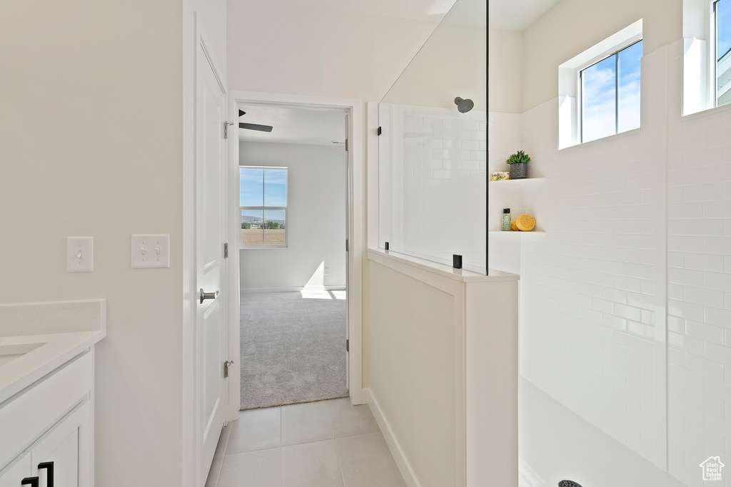 Full bathroom with healthy amount of natural light, a walk in shower, tile patterned floors, and vanity