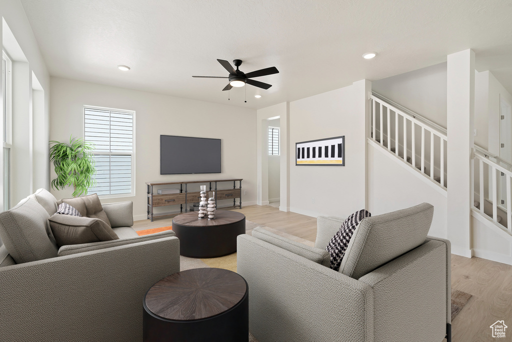 Living area with light wood-style flooring, a ceiling fan, recessed lighting, stairway, and baseboards