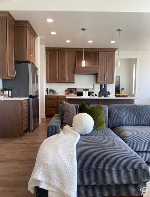 Kitchen with pendant lighting, a breakfast bar, dark wood-type flooring, and stainless steel refrigerator
