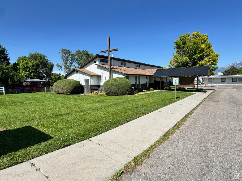 View of front of property with a front yard and a detached carport