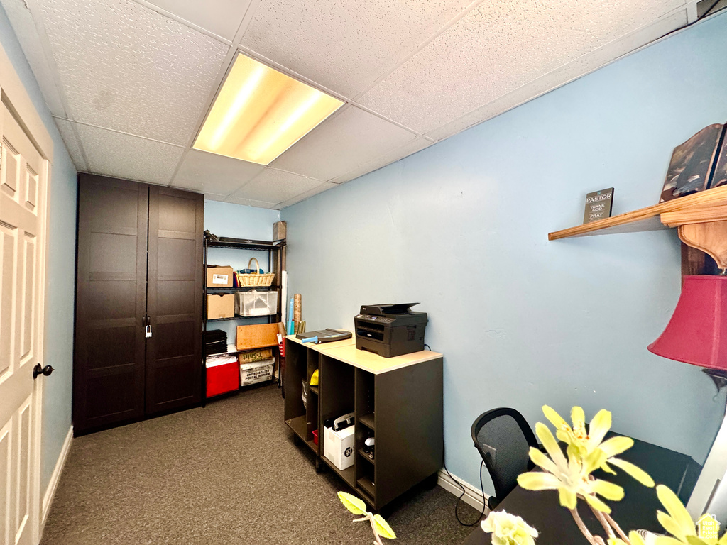 Carpeted office with a paneled ceiling and baseboards