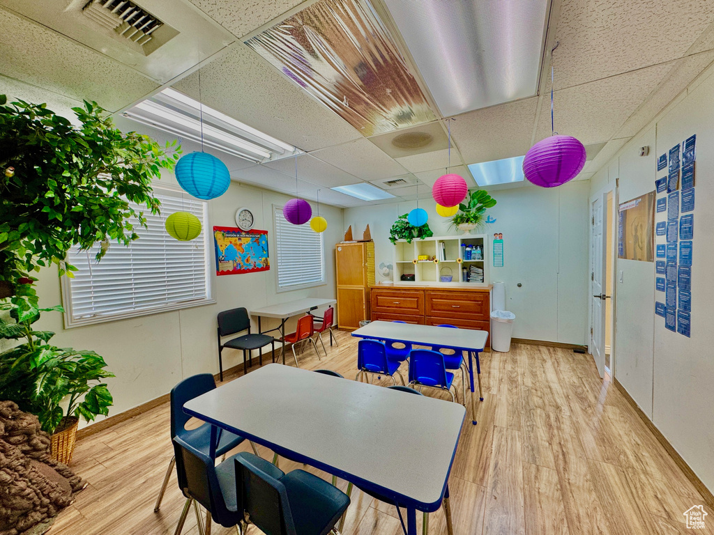 Dining area with a drop ceiling, light wood-style flooring, and baseboards