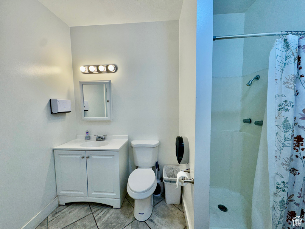 Full bath featuring vanity, toilet, a shower with shower curtain, and baseboards