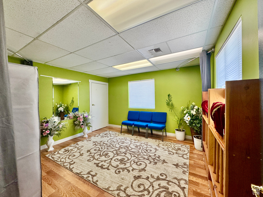 Living area featuring a drop ceiling, wood finished floors, and baseboards