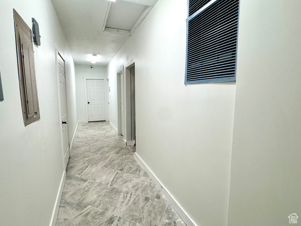 Hall featuring attic access, baseboards, and light marble finish floors