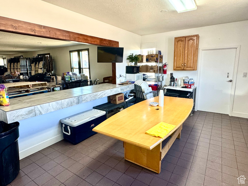 Kitchen featuring dark tile patterned floors, tile counters, a textured ceiling, and open floor plan