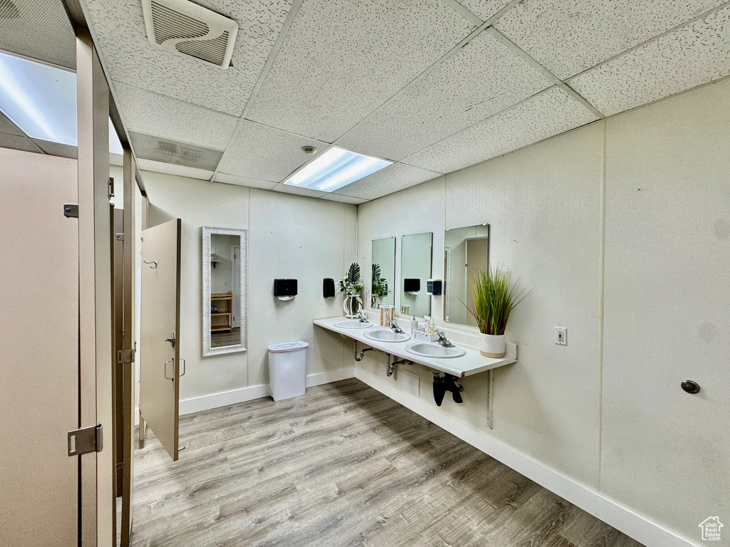 Bathroom with a drop ceiling, wood finished floors, and baseboards