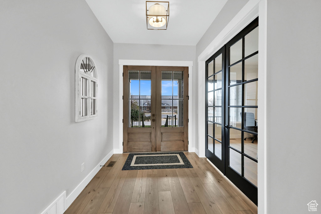 Foyer entrance with french doors, baseboards, and wood-type flooring