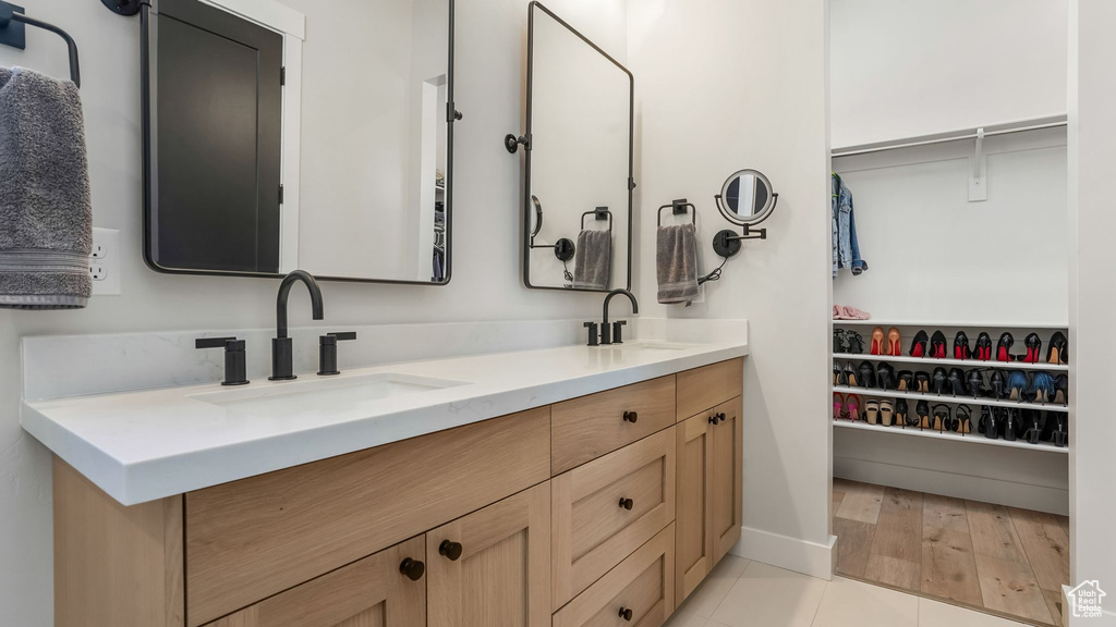 Bathroom with double vanity, a walk in closet, and tile patterned floors