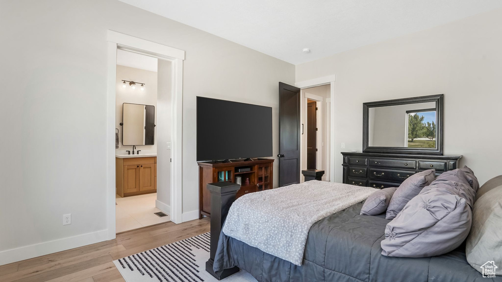 Bedroom featuring light wood-style flooring, a sink, baseboards, and connected bathroom