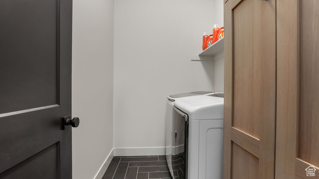 Washroom with washer and dryer, baseboards, and dark tile patterned flooring