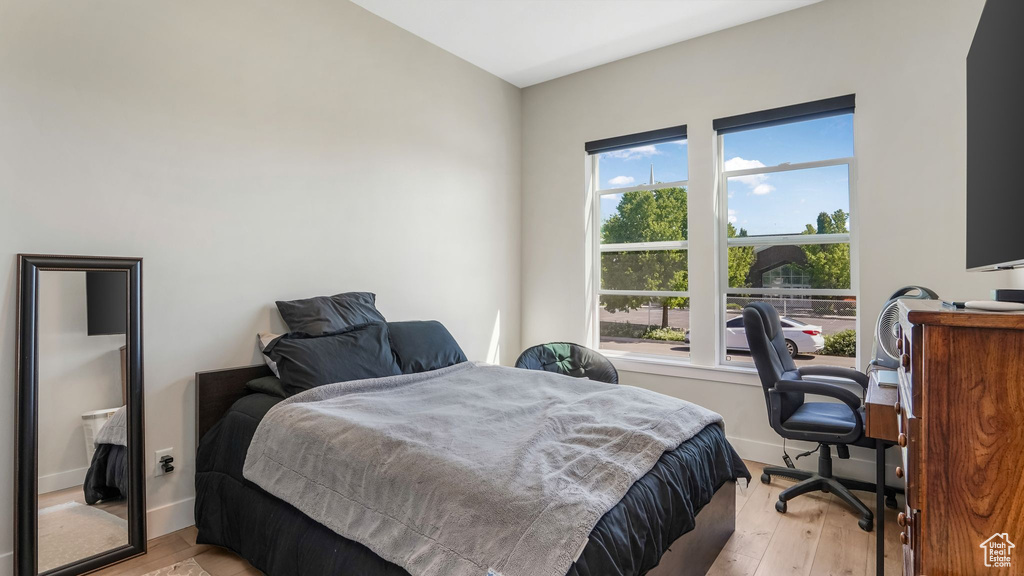 Bedroom featuring light wood finished floors, baseboards, and an office area