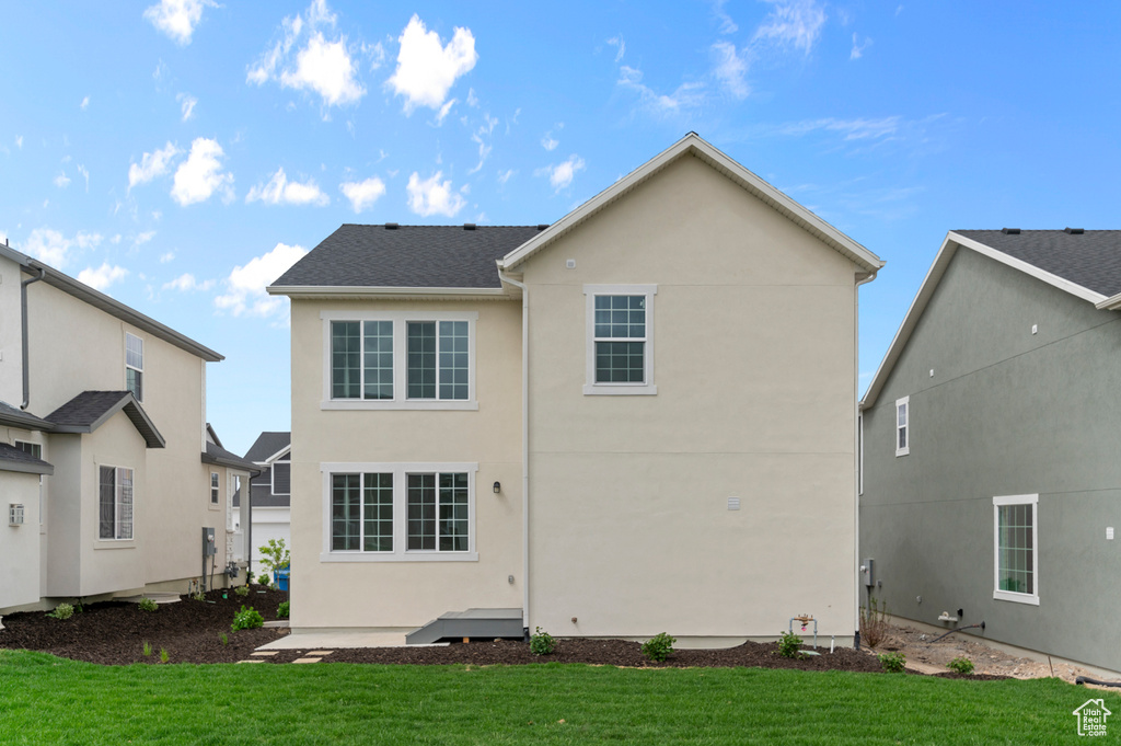 Back of house with stucco siding and a yard