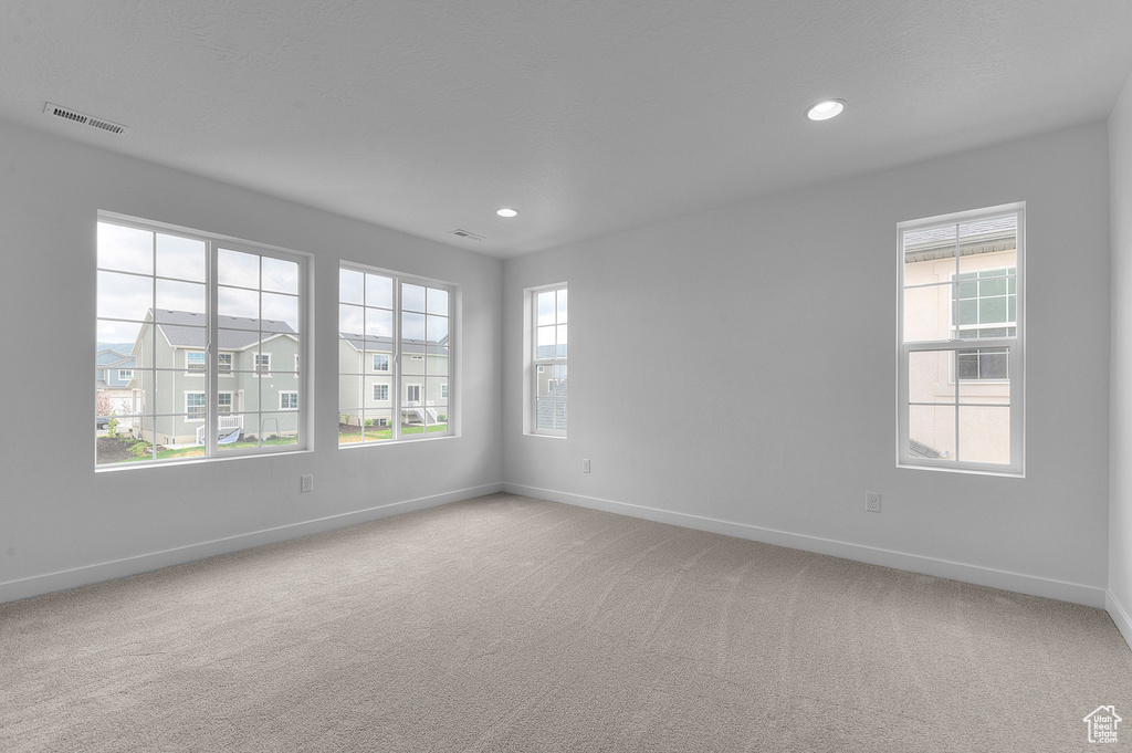Empty room with baseboards, healthy amount of natural light, light colored carpet, and recessed lighting