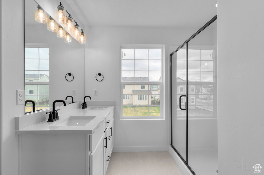 Full bathroom with double vanity, a stall shower, baseboards, and tile patterned floors