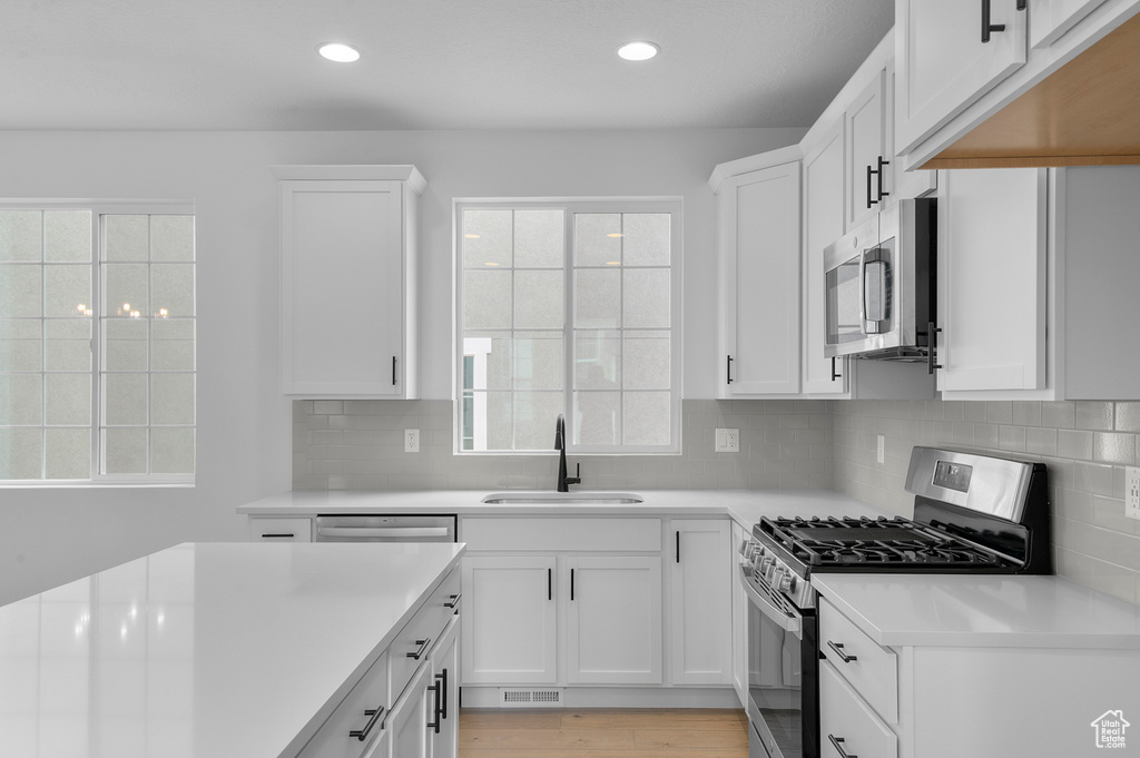 Kitchen featuring a sink, stainless steel appliances, light countertops, tasteful backsplash, and recessed lighting