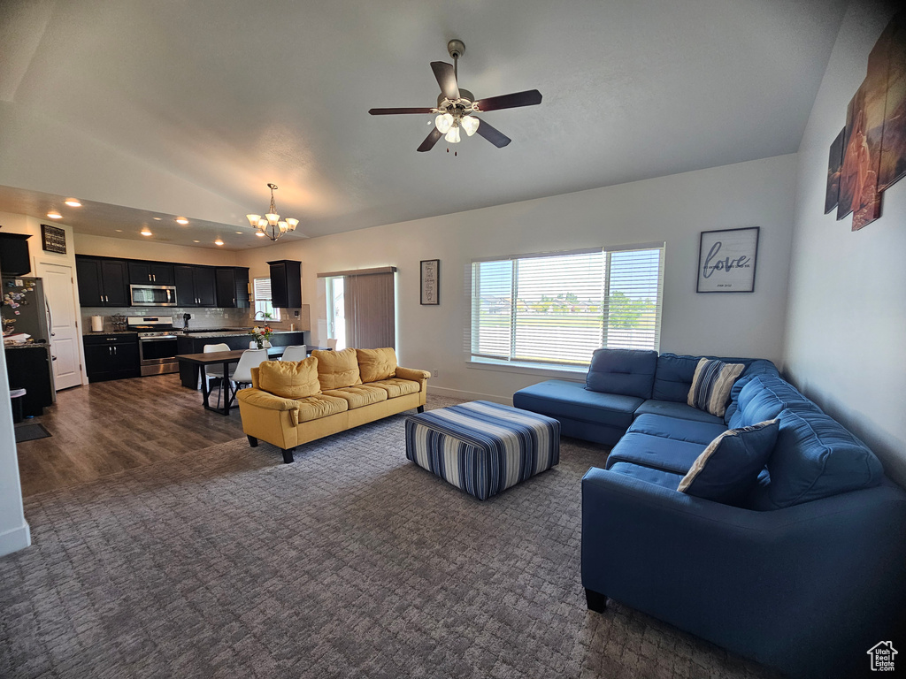 Living room with lofted ceiling, a chandelier, ceiling fan, dark colored carpet, and recessed lighting
