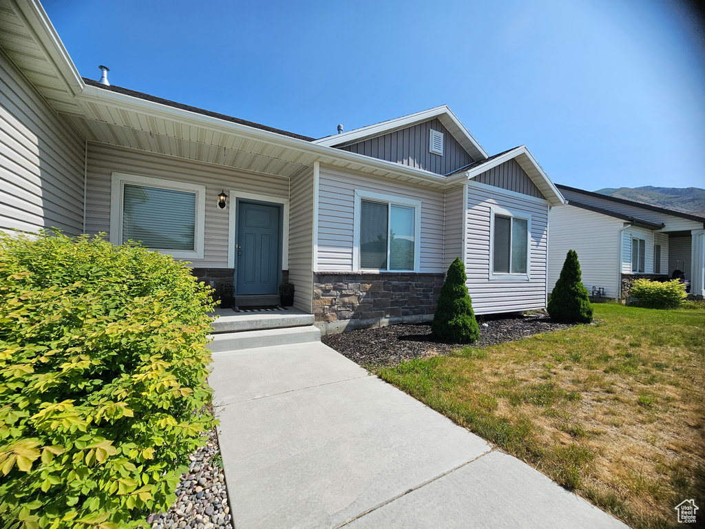 Entrance to property featuring board and batten siding, stone siding, and a yard