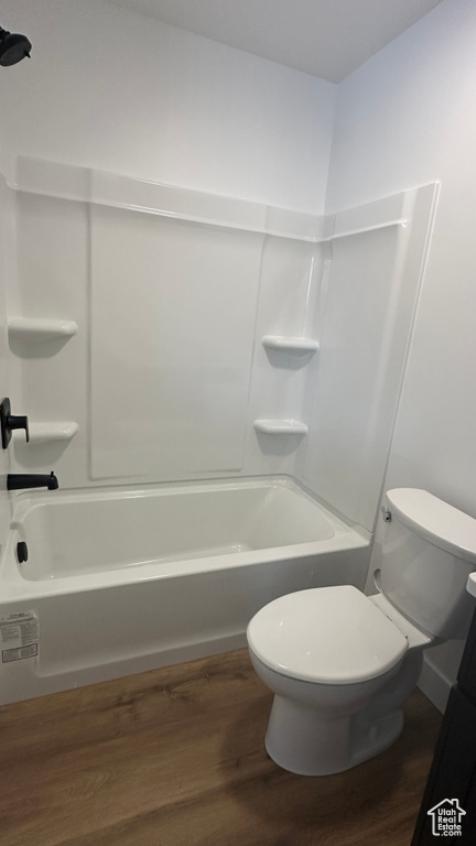 Bathroom with toilet, tub / shower combination, and wood-type flooring