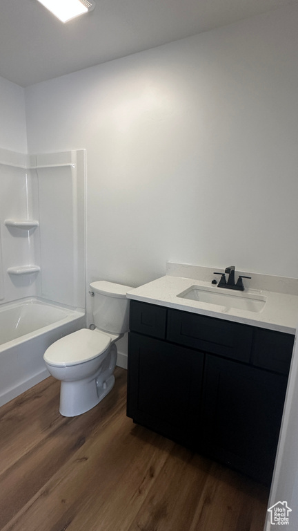 Full bathroom with hardwood / wood-style flooring, shower / bath combination, toilet, and vanity