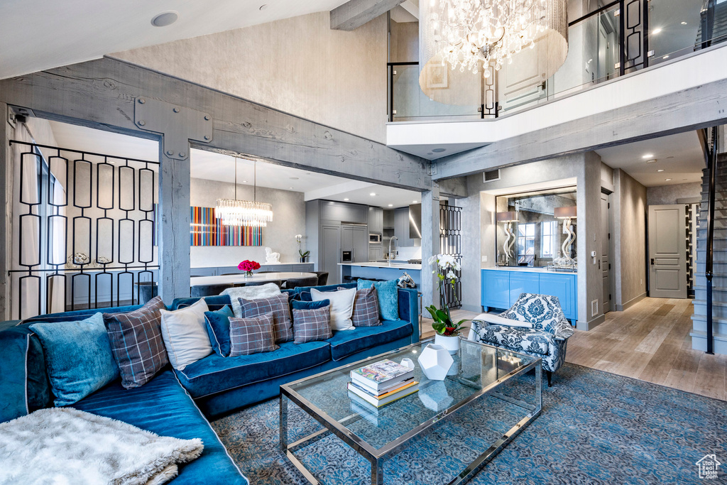 Living room featuring a chandelier, a towering ceiling, wood finished floors, and stairs
