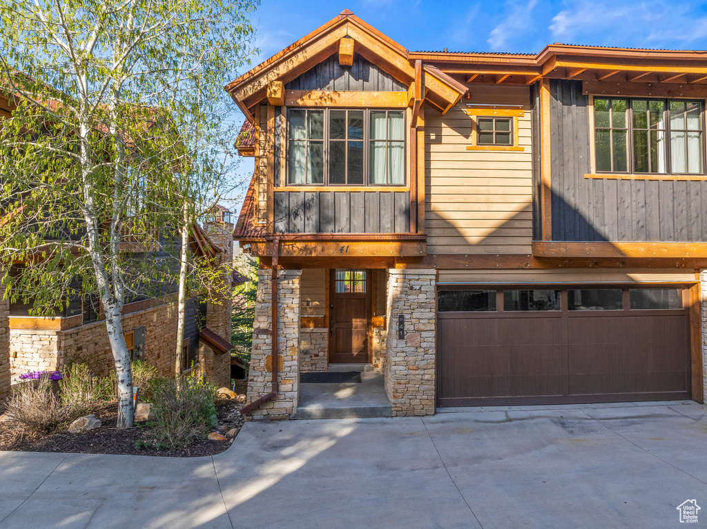 View of front of home featuring a garage, driveway, and stone siding