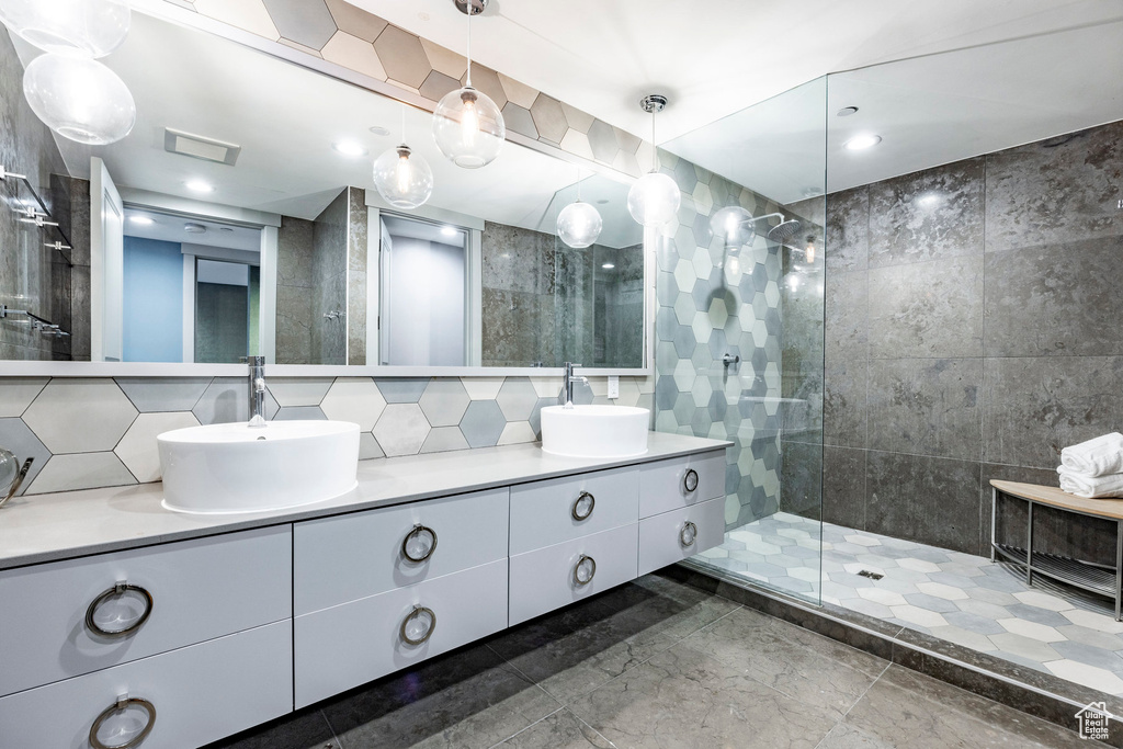 Full bath with double vanity, walk in shower, and tasteful backsplash