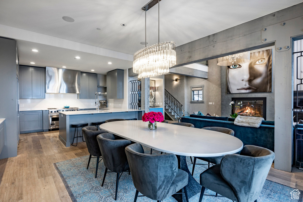 Dining area featuring stairway, light wood finished floors, a glass covered fireplace, a chandelier, and recessed lighting