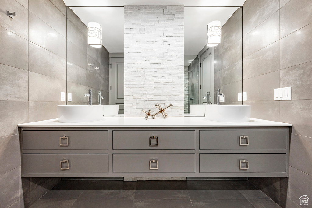 Full bathroom with tile walls, double vanity, and tile patterned flooring