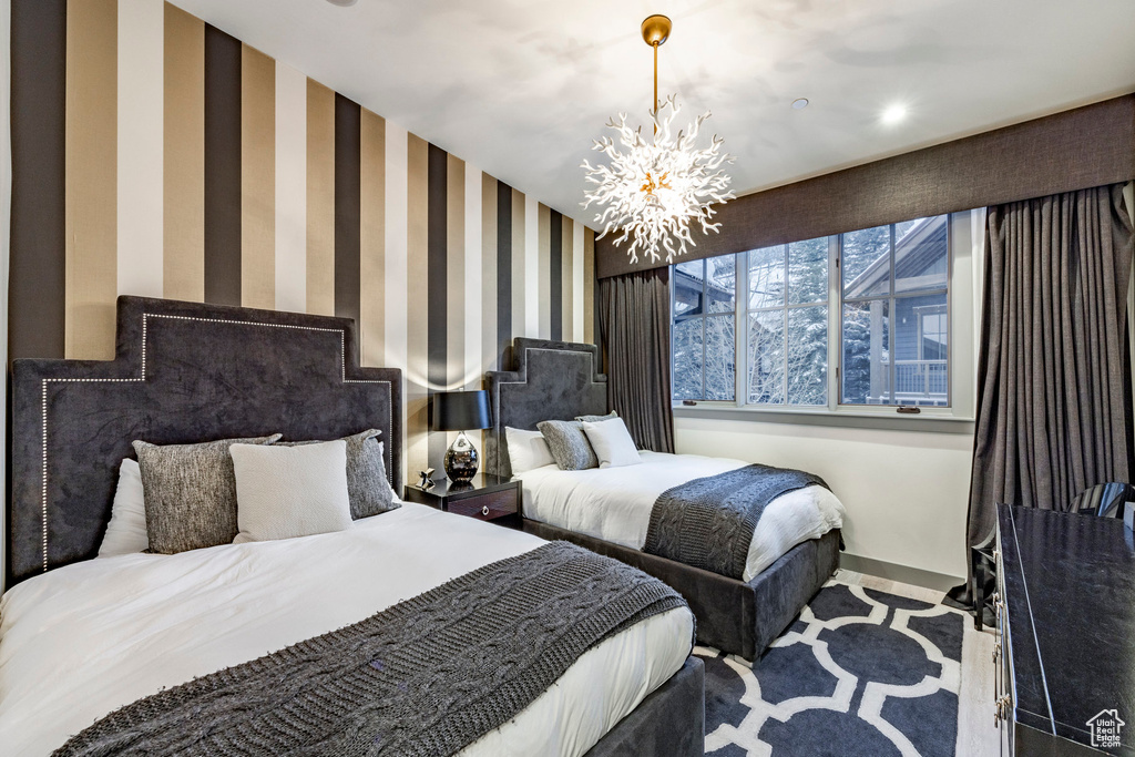 Bedroom with wallpapered walls, a chandelier, baseboards, and carpet