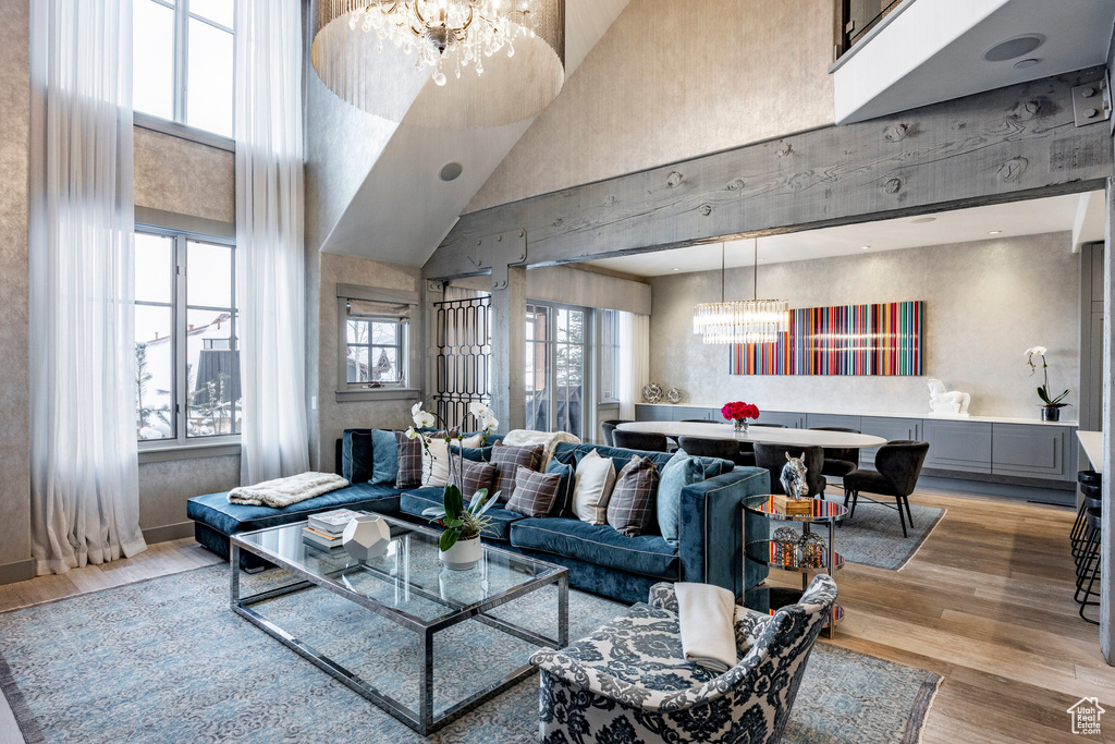 Living area with a chandelier, a towering ceiling, and light wood-style flooring