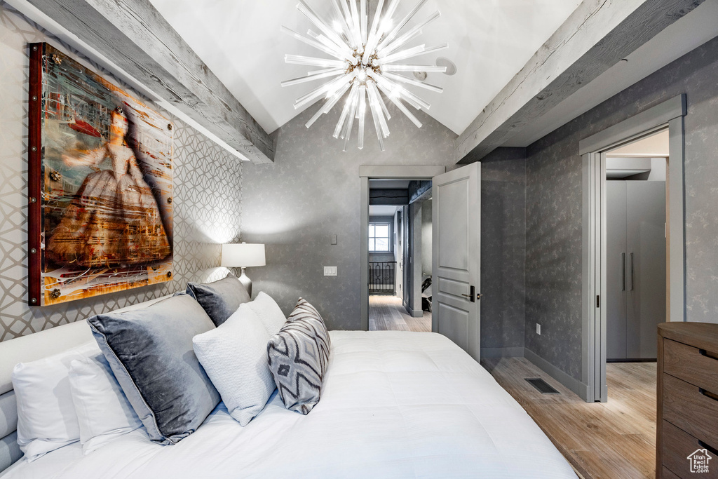 Bedroom with vaulted ceiling, light wood finished floors, a chandelier, and a ceiling fan