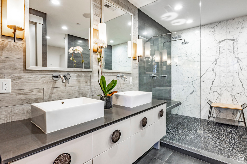 Full bathroom with tile walls, walk in shower, double vanity, decorative backsplash, and recessed lighting