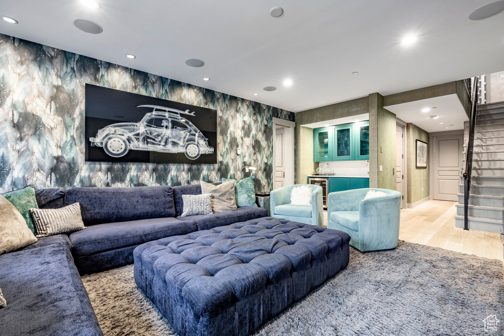 Living room featuring wood finished floors, stairs, wallpapered walls, recessed lighting, and bar
