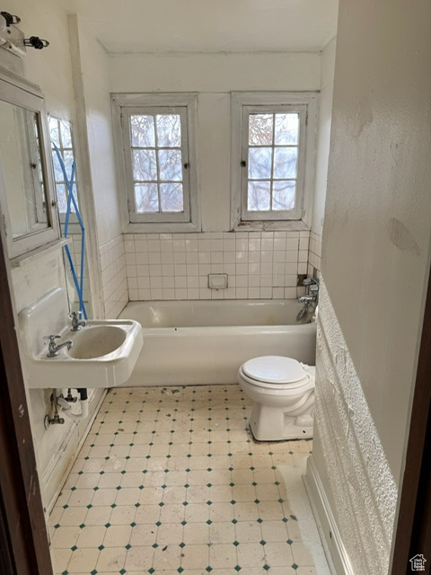 Bathroom featuring toilet, a tub, and sink