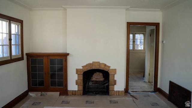 Unfurnished living room featuring a healthy amount of sunlight, crown molding, and french doors