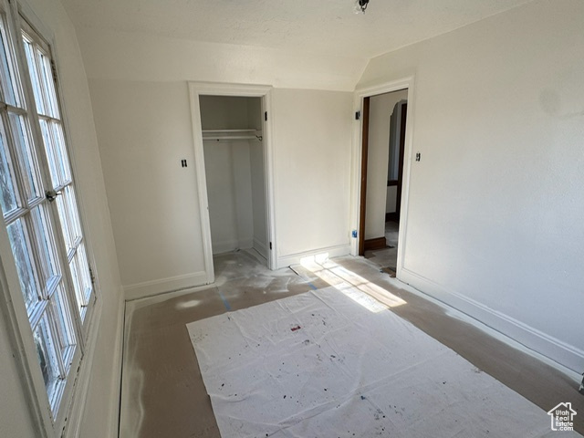 Unfurnished bedroom with vaulted ceiling and a closet
