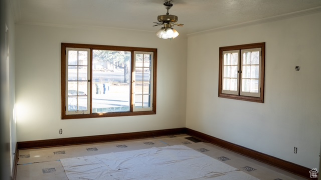 Unfurnished room featuring ceiling fan, crown molding, and light tile patterned floors