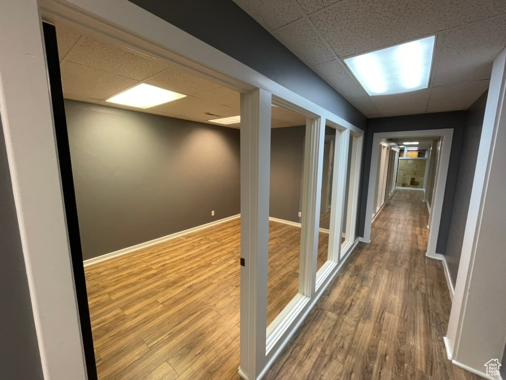 Hallway with a paneled ceiling and hardwood / wood-style floors