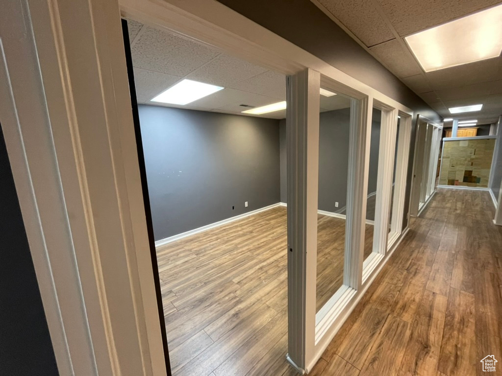 Corridor with a paneled ceiling and hardwood / wood-style flooring