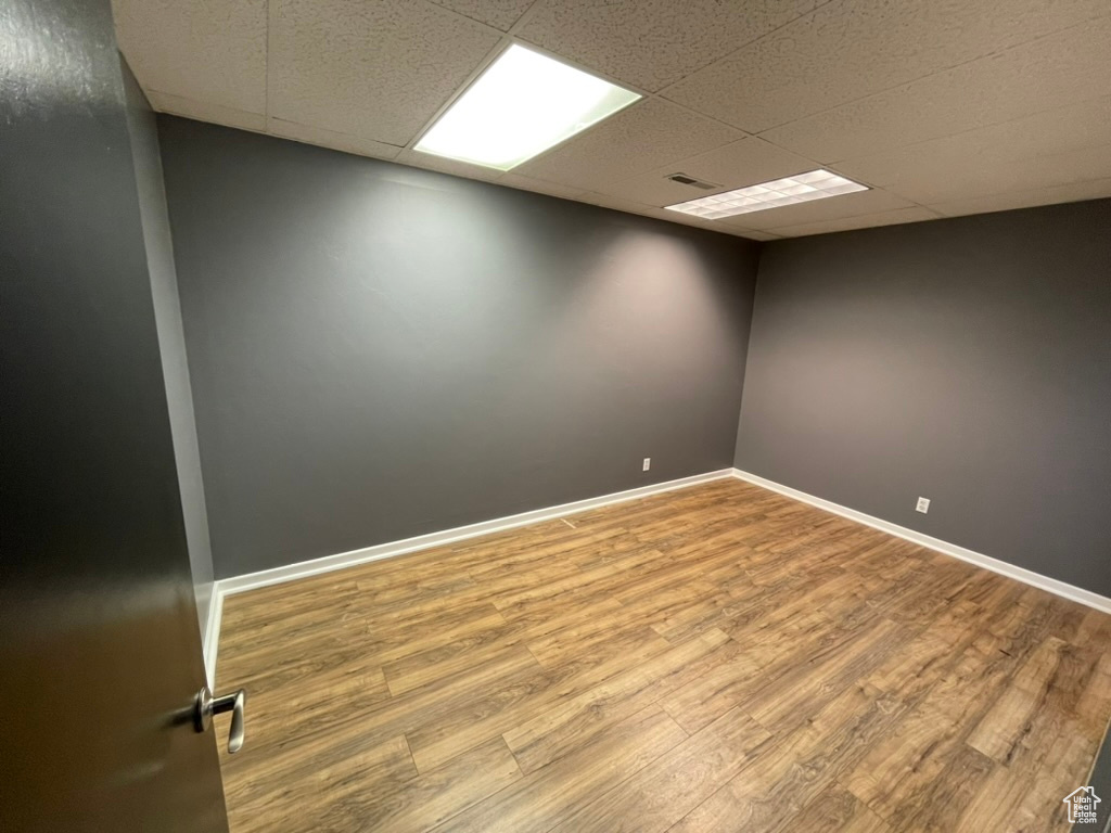 Empty room featuring hardwood / wood-style floors and a drop ceiling