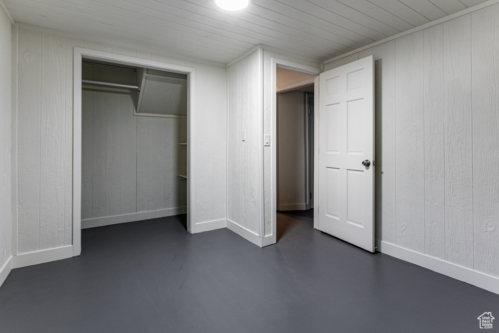 Unfurnished bedroom featuring wood walls, wood ceiling, and a closet